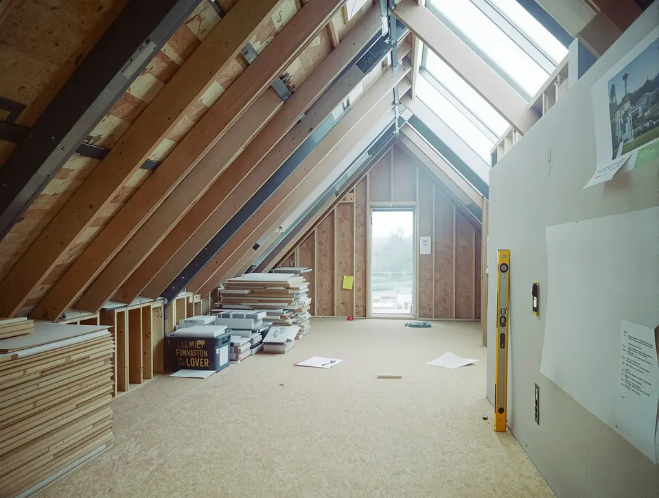 A loft conversion under construction, exposed steel beam ridge, timber stud framing.